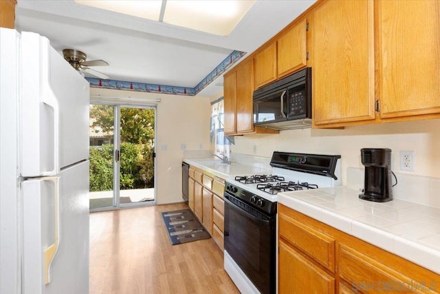 kitchen with ceiling fan, tile countertops, light hardwood / wood-style floors, sink, and white appliances