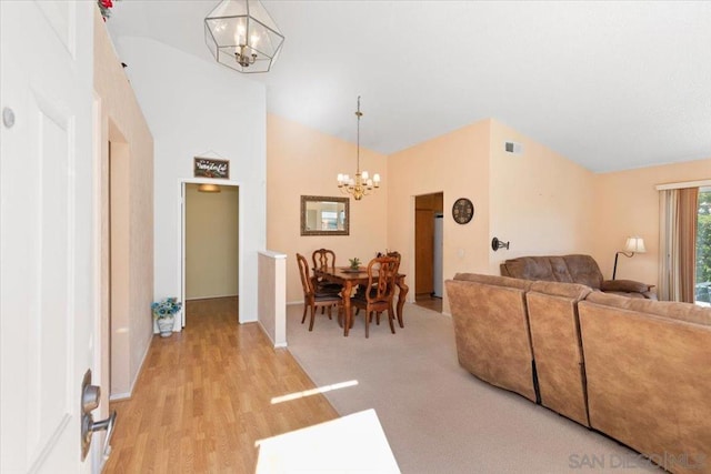 living room featuring a notable chandelier, high vaulted ceiling, and light hardwood / wood-style floors