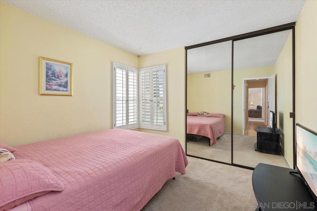 bedroom with a closet, a textured ceiling, and light colored carpet