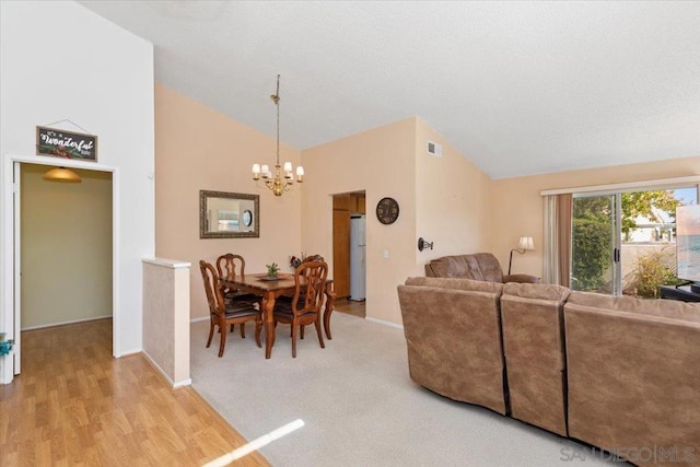 living room with vaulted ceiling, light hardwood / wood-style flooring, and an inviting chandelier