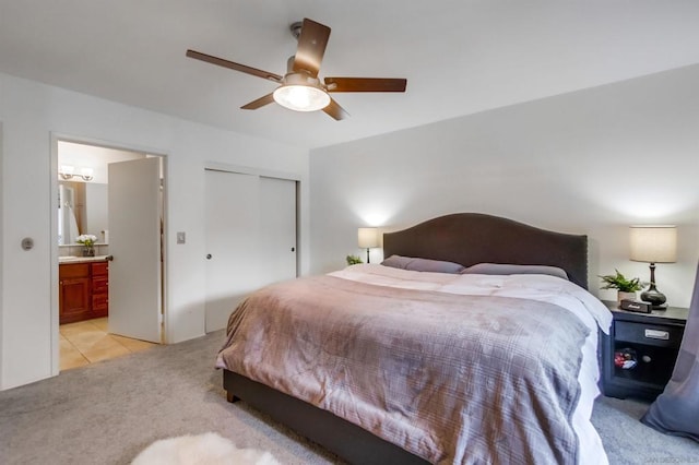 bedroom with ceiling fan, light carpet, connected bathroom, and a closet