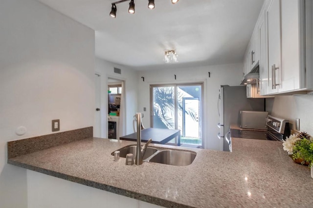 kitchen featuring white cabinets, sink, stainless steel range, and track lighting