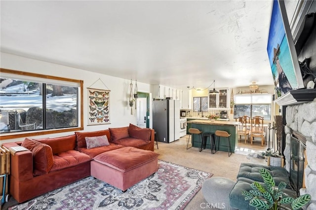 living room featuring a fireplace, light carpet, and plenty of natural light