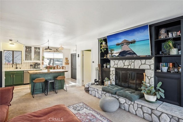 living room featuring a fireplace, light carpet, and sink