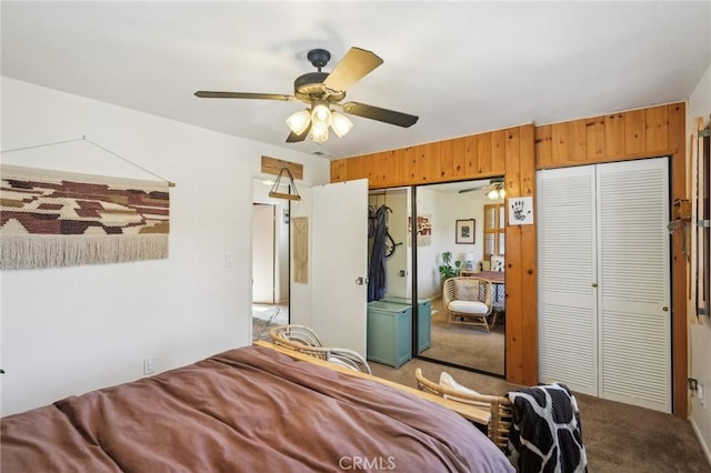 carpeted bedroom featuring two closets, ceiling fan, and wood walls