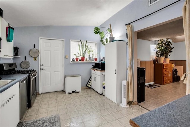 kitchen with white cabinets, stainless steel appliances, and vaulted ceiling