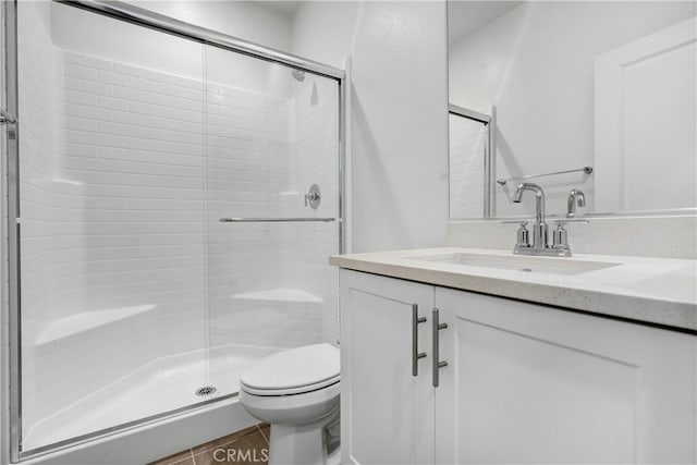 bathroom featuring vanity, toilet, a shower with shower door, and tile patterned flooring