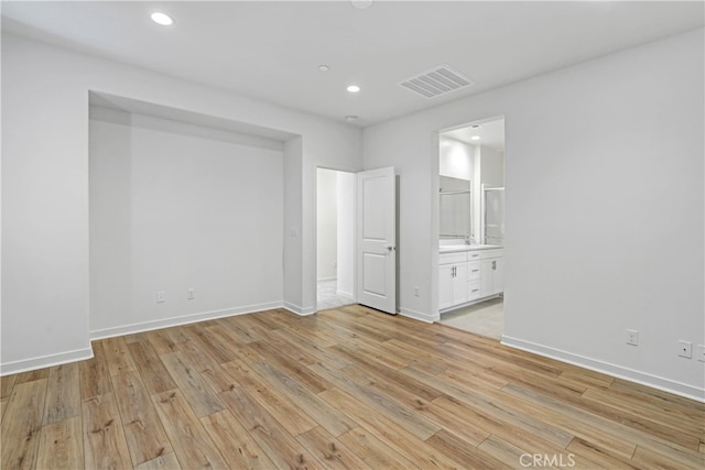 unfurnished bedroom featuring connected bathroom and light hardwood / wood-style flooring