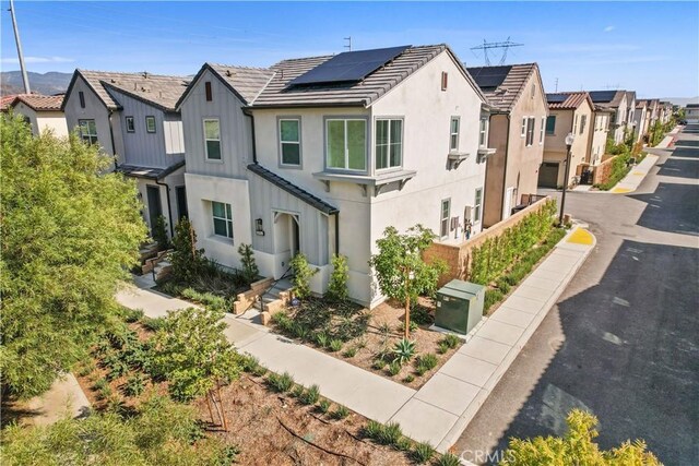 15974 Jamie Ln Unit 1, Fontana, CA 92336 - view of front facade with a residential view, solar panels, stucco siding, a tile roof, and board and batten siding