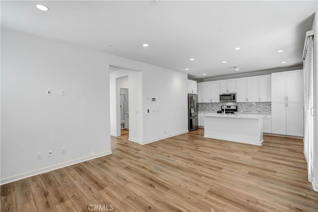 kitchen with an island with sink, stainless steel appliances, and light wood-type flooring