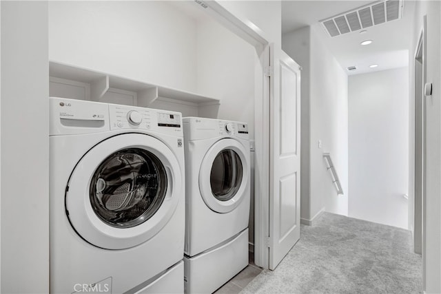 clothes washing area featuring washing machine and dryer and light colored carpet