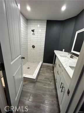 bathroom featuring tiled shower and vanity