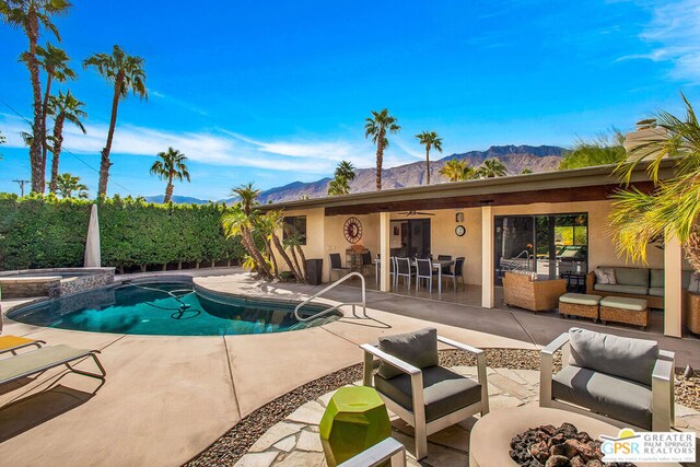 view of swimming pool with an outdoor living space, a patio area, a mountain view, and an in ground hot tub