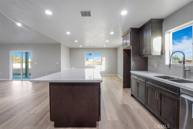 kitchen featuring dishwasher, a center island, sink, and light hardwood / wood-style flooring