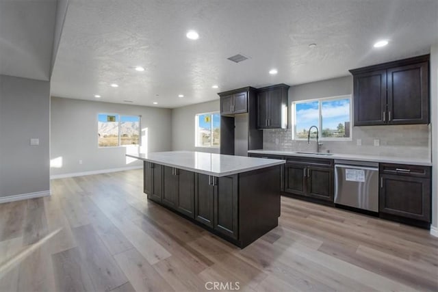 kitchen featuring a center island, backsplash, sink, stainless steel dishwasher, and light hardwood / wood-style floors