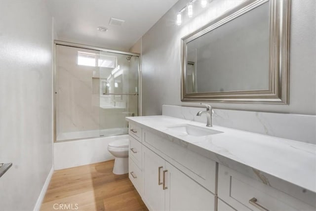 full bathroom with enclosed tub / shower combo, toilet, wood-type flooring, and vanity