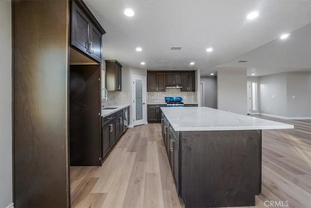 kitchen featuring dark brown cabinetry, a center island, sink, stainless steel appliances, and light hardwood / wood-style floors