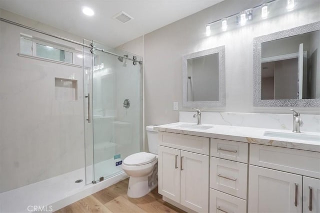 bathroom featuring hardwood / wood-style flooring, vanity, toilet, and a shower with shower door