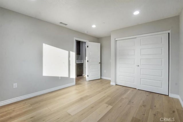 unfurnished bedroom with light hardwood / wood-style flooring and a closet