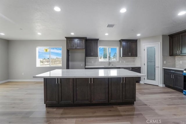 kitchen featuring backsplash, light hardwood / wood-style flooring, a kitchen island, and sink