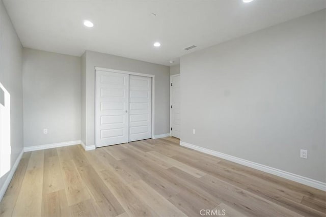 unfurnished bedroom featuring light hardwood / wood-style floors and a closet