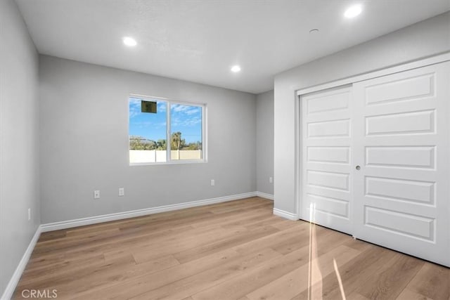 unfurnished bedroom with a closet and light hardwood / wood-style floors