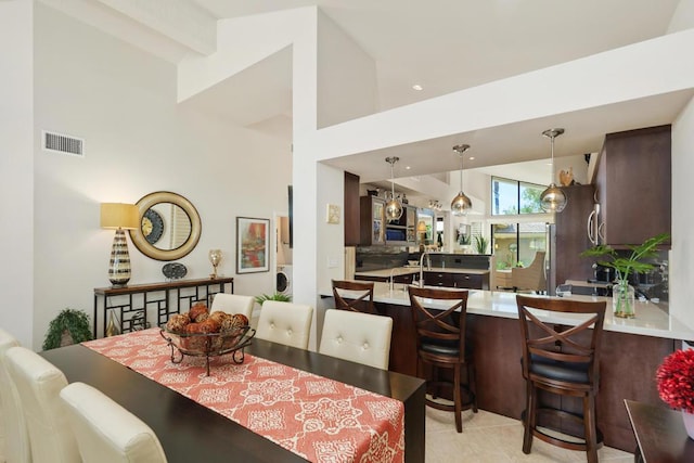 dining room with light tile patterned floors and high vaulted ceiling