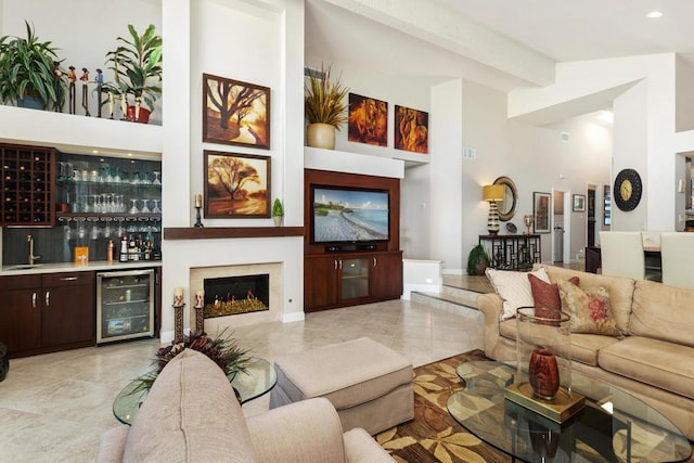 living room with beamed ceiling, indoor wet bar, a towering ceiling, and wine cooler