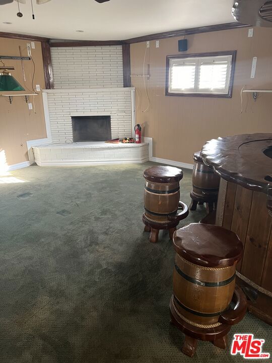 carpeted living room featuring a fireplace and ornamental molding