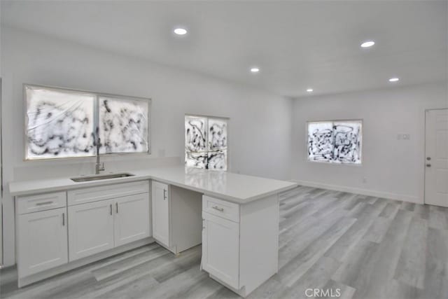 kitchen with sink, white cabinets, and light wood-type flooring