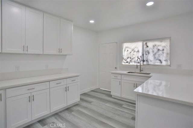 kitchen featuring white cabinets, light hardwood / wood-style flooring, and sink