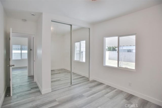 unfurnished bedroom with light hardwood / wood-style floors and a closet