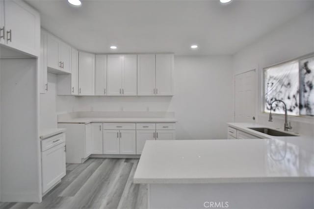 kitchen featuring sink, white cabinets, and light hardwood / wood-style flooring