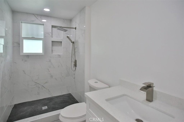 bathroom with vanity, toilet, and tiled shower