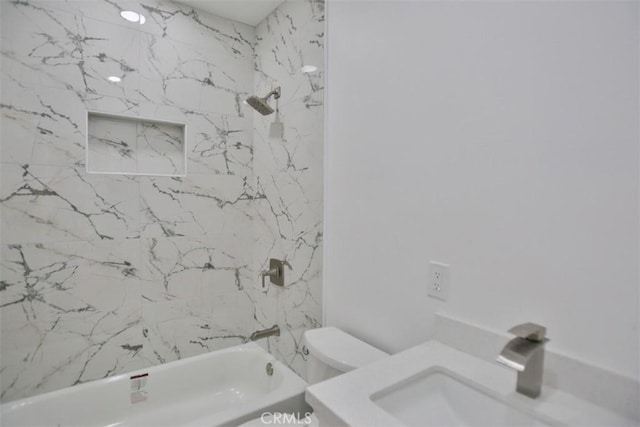 full bathroom featuring tiled shower / bath combo, toilet, and sink