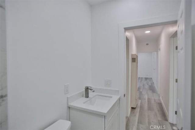 bathroom with hardwood / wood-style floors, vanity, and toilet