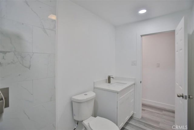 bathroom with hardwood / wood-style floors, vanity, and toilet