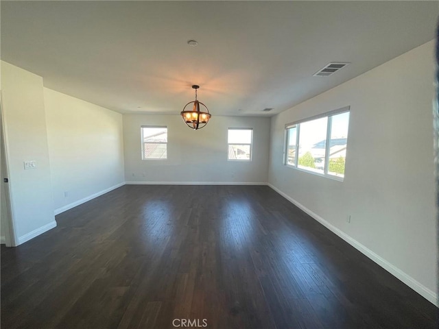 spare room featuring a chandelier and dark hardwood / wood-style floors