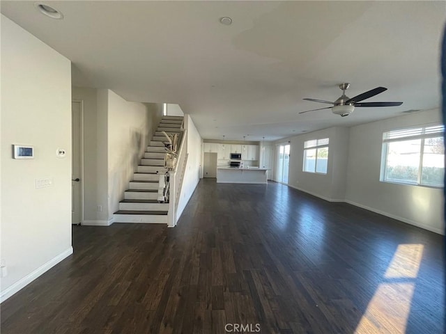 unfurnished living room featuring ceiling fan and dark wood-type flooring