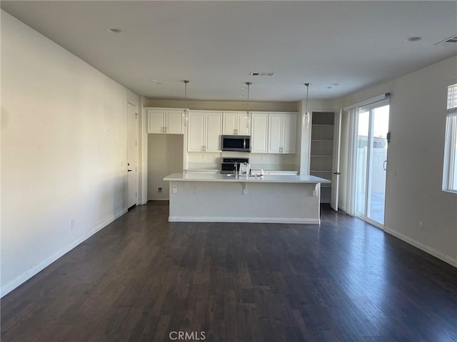 kitchen with stainless steel appliances, white cabinetry, a kitchen island with sink, and dark wood-type flooring