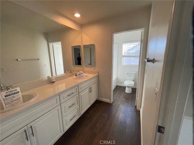 bathroom featuring hardwood / wood-style floors, vanity, toilet, and a bathtub