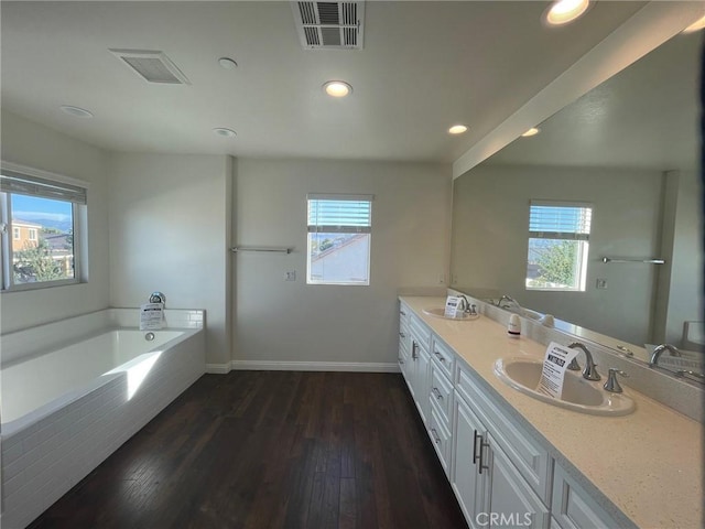 bathroom featuring tiled bath, hardwood / wood-style floors, and a healthy amount of sunlight