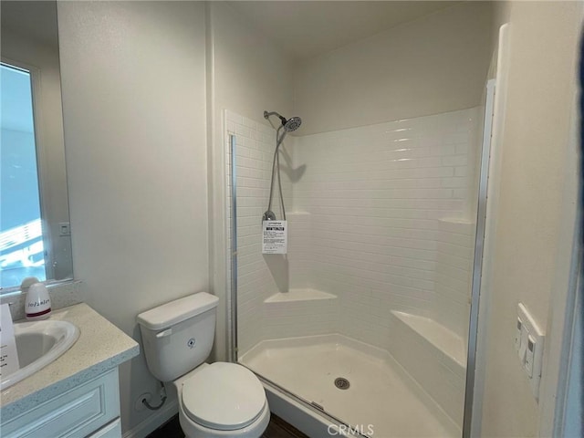 bathroom featuring tiled shower, vanity, and toilet