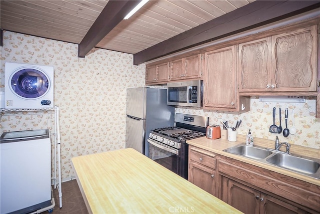 kitchen with sink, stainless steel appliances, wooden ceiling, beam ceiling, and stacked washer and clothes dryer