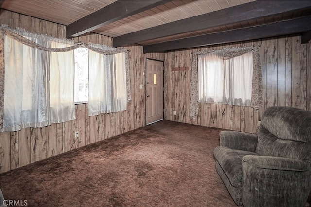 living area featuring wood ceiling, wood walls, carpet, and beamed ceiling