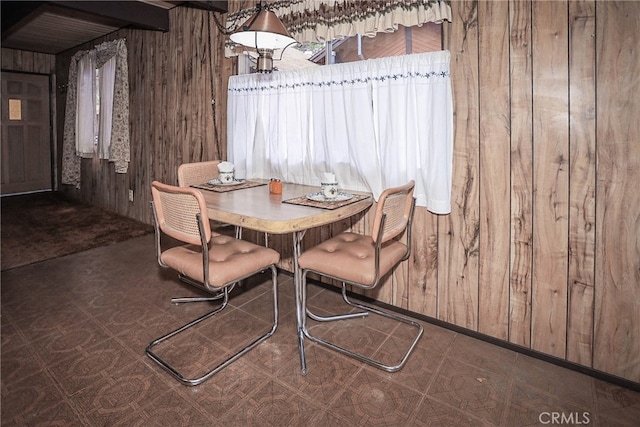 unfurnished dining area featuring beam ceiling and wood walls