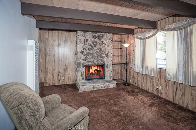 carpeted living room featuring beam ceiling, wooden walls, wood ceiling, and a fireplace