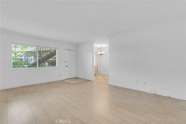 empty room featuring light wood-type flooring, an inviting chandelier, and ornamental molding