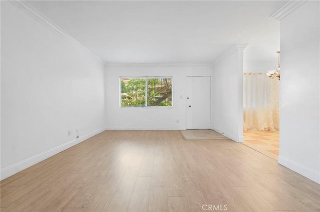 empty room featuring an inviting chandelier, ornamental molding, and light hardwood / wood-style flooring