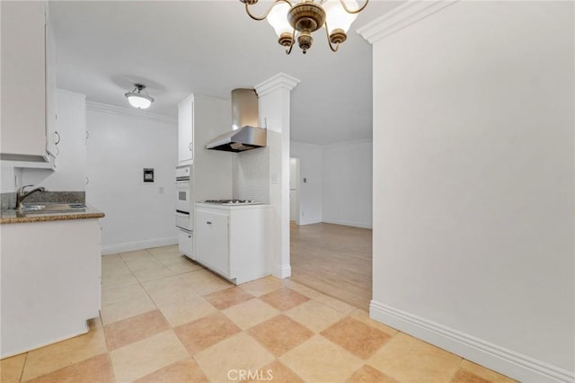 kitchen with crown molding, sink, wall chimney range hood, white cabinets, and a chandelier